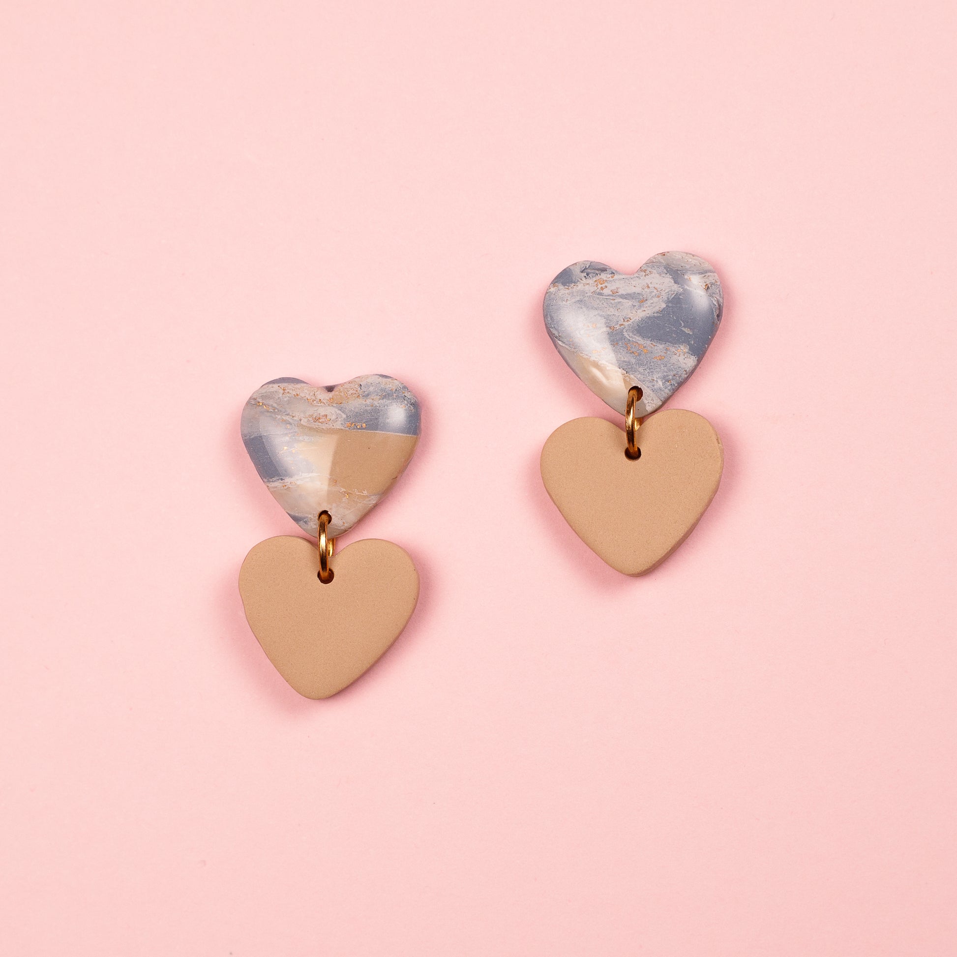 Pendientes de arcilla polimérica y acero inoxidable hechos a mano. Dos corazones, uno cuelga debajo de otro.