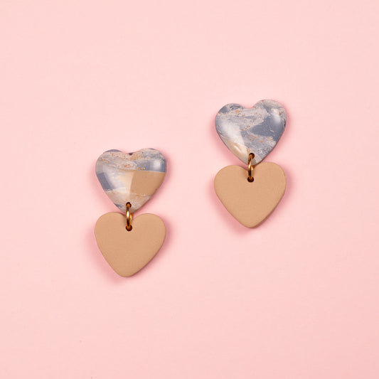 Pendientes de arcilla polimérica y acero inoxidable hechos a mano. Dos corazones, uno cuelga debajo de otro.