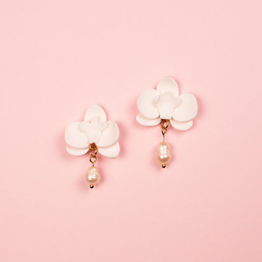PEndientes hechos a mano con arcilla polimérica y acero inoxidable en forma de orquídea adornados con una perla.