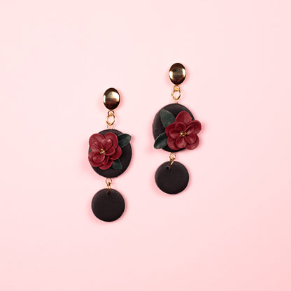 Pendientes de arcilla polimérica y acero inoxidable hechos a mano con forma de circulos y una flor en medio.