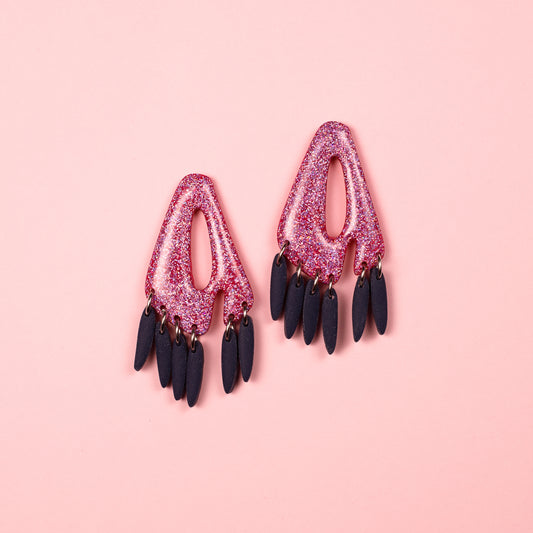 Pendientes de arcilla polimérica y acero inoxidable hechos a mano con formas geométricas y colores rosa y azul marino.